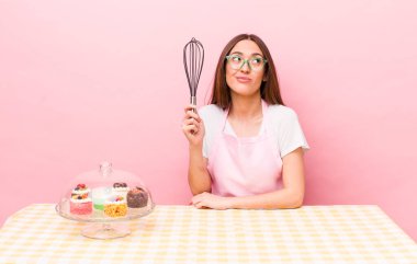 İspanyol güzel kadın omuz silkiyor, kafası karışık ve kararsız. Ev yapımı kek konsepti