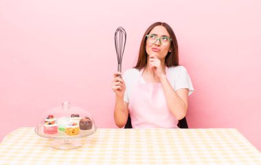 Hispanik güzel kadın düşünüyor, kuşkulu ve şaşkın hissediyor. Ev yapımı kek konsepti