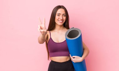 İspanyol güzel kadın gülümsüyor ve mutlu görünüyor, zafer ya da barış işareti yapıyor. fitness ve yoga konsepti