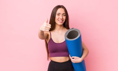 İspanyol güzel kadın gururlu, başparmağıyla olumlu gülümsüyor. fitness ve yoga konsepti