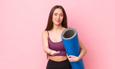 İspanyol güzel kadın gülerek dostça bir teklifte bulunuyor ve bir konsept gösteriyor. fitness ve yoga konsepti