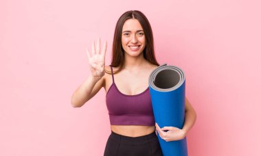 İspanyol güzel kadın gülümsüyor ve arkadaş canlısı görünüyor, dört numarayı gösteriyor. fitness ve yoga konsepti