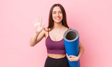 İspanyol güzel kadın gülümsüyor ve arkadaş canlısı görünüyor, beş numarayı gösteriyor. fitness ve yoga konsepti