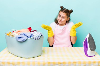 Genç ve güzel bir kadın şaşkın, şaşkın ve şüpheci hissediyor. ev işi kavramı