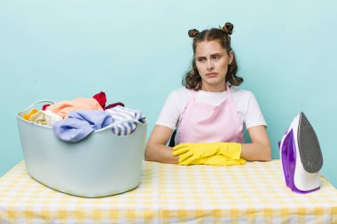 Genç, güzel bir kadın üzgün, üzgün ya da kızgın hissediyor ve yan tarafa bakıyor. ev işi kavramı