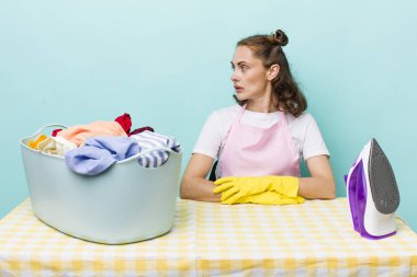 Profil görünümlü genç, güzel bir kadın hayal kuruyor ya da hayal kuruyor. ev işi kavramı