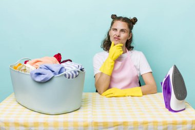 Genç, güzel bir kadın düşünüyor, kuşkulu ve şaşkın hissediyor. ev işi kavramı