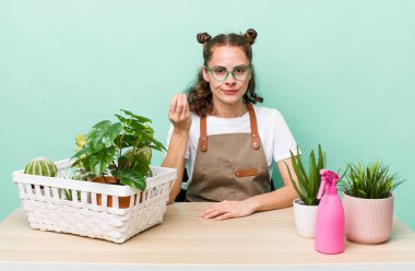 young pretty woman  making capice or money gesture, telling you to pay. gardering plants concept