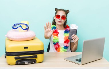 Genç ve güzel bir kadın ciddi görünüyor. Avuç içini gösteriyor. Durdurma hareketi yapıyor. seyahat kavramı