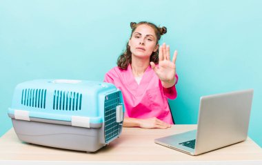 Genç ve güzel bir kadın ciddi görünüyor. Avuç içini gösteriyor. Durdurma hareketi yapıyor. Veterinerlik kavramı