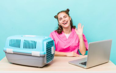 Genç ve güzel bir bayan mutlu bir şekilde gülümsüyor, el sallıyor, sizi selamlıyor ve selamlıyor. Veterinerlik kavramı