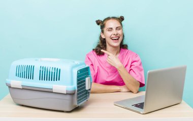 Genç, güzel bir kadın neşeyle gülümsüyor, mutlu hissediyor ve bir tarafı işaret ediyor. Veterinerlik kavramı