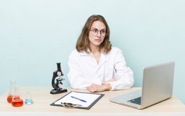 Genç, güzel bir kadın üzgün, üzgün ya da kızgın hissediyor ve yan tarafa bakıyor. Mikroskop konseptine sahip bilim adamı