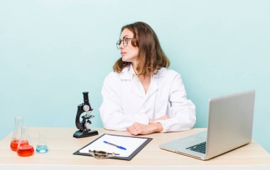 Profil görünümlü genç, güzel bir kadın hayal kuruyor ya da hayal kuruyor. Mikroskop konseptine sahip bilim adamı