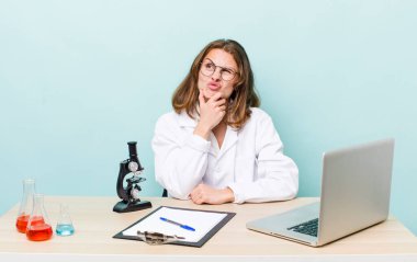 Genç, güzel bir kadın düşünüyor, kuşkulu ve şaşkın hissediyor. Mikroskop konseptine sahip bilim adamı