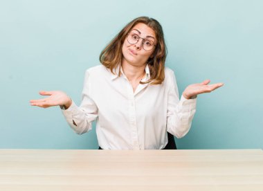 Genç ve güzel bir kadın şaşkın, şaşkın ve şüpheci hissediyor. masa ve iş konsepti