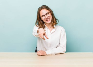 Genç ve güzel bir kadın kamerayı işaret ederek seni seçiyor. masa ve iş konsepti