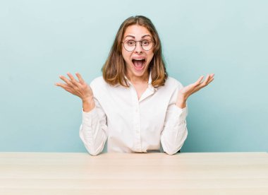 Genç ve güzel bir kadın inanılmaz bir şey karşısında kendini mutlu ve şaşkın hissediyor. masa ve iş konsepti