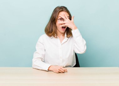 Genç, güzel bir kadın şok olmuş, korkmuş ya da korkmuş görünüyor. masa ve iş konsepti