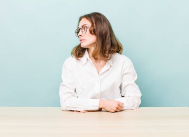 young pretty woman  on profile view thinking, imagining or daydreaming. desk and business concept