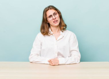 Genç ve güzel bir kadın şaşkın ve şaşkın hissediyor. masa ve iş konsepti