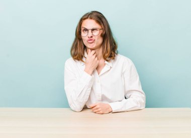 Genç, güzel bir kadın düşünüyor, kuşkulu ve şaşkın hissediyor. masa ve iş konsepti