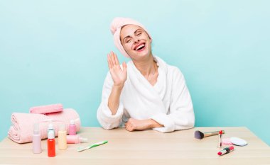 Genç ve güzel bir bayan mutlu bir şekilde gülümsüyor, el sallıyor, sizi selamlıyor ve selamlıyor. uydurma konsepti