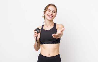 Genç ve güzel bir kadın arkadaşça gülümsüyor ve bir konsept sunuyor. fitness konsepti ve kronometre