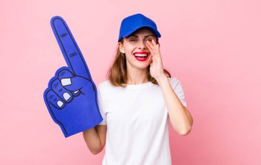 Genç, güzel bir kadın kendini mutlu hissediyor. Elleri ağzının kenarında bağırıyor. Bir numaralı hayran konsepti