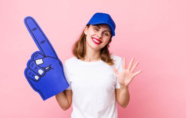 Genç, güzel bir bayan gülümsüyor ve arkadaş canlısı görünüyor, beş numarayı gösteriyor. Bir numaralı hayran konsepti