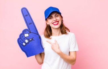 Genç, güzel bir kadın neşeyle gülümsüyor, mutlu hissediyor ve bir tarafı işaret ediyor. Bir numaralı hayran konsepti