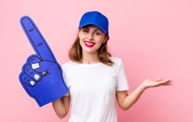 Genç, güzel bir kadın neşeyle gülümsüyor, mutlu hissediyor ve bir konsept gösteriyor. Bir numaralı hayran konsepti