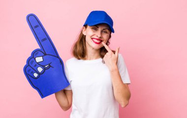 Genç ve güzel bir kadın, kendine güvenerek gülümsüyor. Bir numaralı hayran konsepti