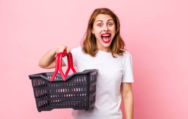 Genç ve güzel bir kadın mutlu ve hoş bir şekilde şaşırmış görünüyor. boş alışveriş sepeti kavramı