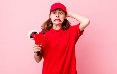 Genç ve güzel bir kadın gergin, endişeli ya da korkmuş hissediyor. Elleri başının üstünde. Şirket paketleyici çalışanı