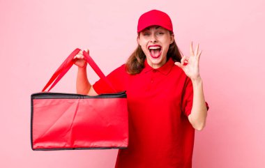 Genç ve güzel bir kadın kendini mutlu hissediyor. Onayını iyi bir hareketle gösteriyor. Pizza teslimatı kavramı