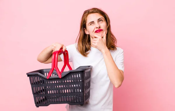 Young Pretty Woman Thinking Feeling Doubtful Confused Empty Shopping Basket — Φωτογραφία Αρχείου