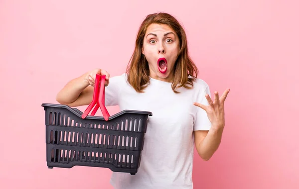 Young Pretty Woman Feeling Extremely Shocked Surprised Empty Shopping Basket — Stockfoto