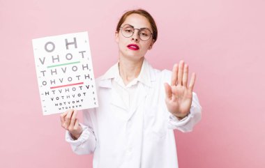 Genç ve güzel bir kadın ciddi görünüyor. Avuç içini gösteriyor. Durdurma hareketi yapıyor. Optik görüş testi konsepti. Mikroskop konseptine sahip bilim adamı