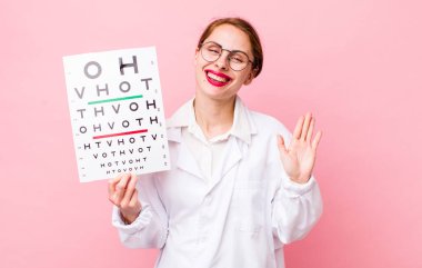 Genç ve güzel bir bayan mutlu bir şekilde gülümsüyor, el sallıyor, sizi selamlıyor ve selamlıyor. Optik görüş testi konsepti. Mikroskop konseptine sahip bilim adamı