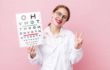 Genç, güzel bir bayan gülümsüyor ve iki numarayı gösteriyor. Optik görüş testi konsepti. Mikroskop konseptine sahip bilim adamı