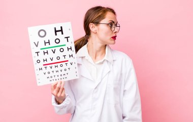 Profil görünümlü genç, güzel bir kadın hayal kuruyor ya da hayal kuruyor. Optik görüş testi konsepti. Mikroskop konseptine sahip bilim adamı