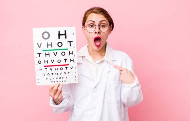 Şok olmuş ve ağzı açık, kendini gösteren genç ve güzel bir kadın. Optik görüş testi konsepti. Mikroskop konseptine sahip bilim adamı