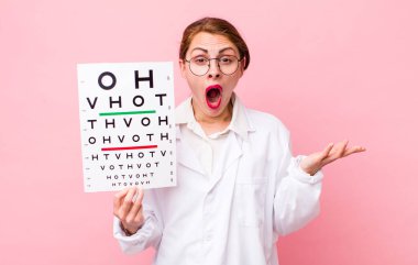 Genç ve güzel bir kadın şaşırmış ve şok olmuş görünüyor. Çenesi düşmüş ve elinde bir nesne tutuyor. Optik görüş testi konsepti. Mikroskop konseptine sahip bilim adamı