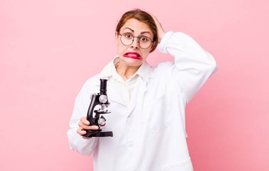 Genç ve güzel bir kadın gergin, endişeli ya da korkmuş hissediyor. Elleri başının üstünde. Mikroskop konseptine sahip bilim adamı