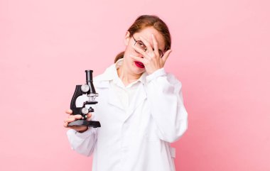 Genç ve güzel bir kadın sıkıcı, bıkkın ve uykulu hissediyor. Mikroskop konseptine sahip bilim adamı