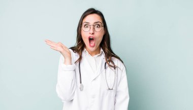 young pretty woman  looking surprised and shocked, with jaw dropped holding an object. physician concept