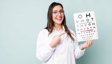 young pretty woman  smiling cheerfully, feeling happy and pointing to the side. optical vision test concept