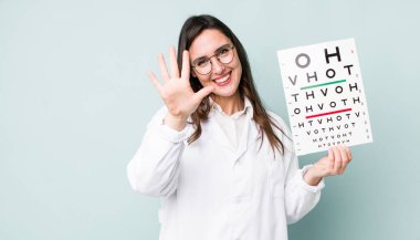 young pretty woman  smiling and looking friendly, showing number five. optical vision test concept