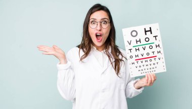 young pretty woman  looking surprised and shocked, with jaw dropped holding an object. optical vision test concept